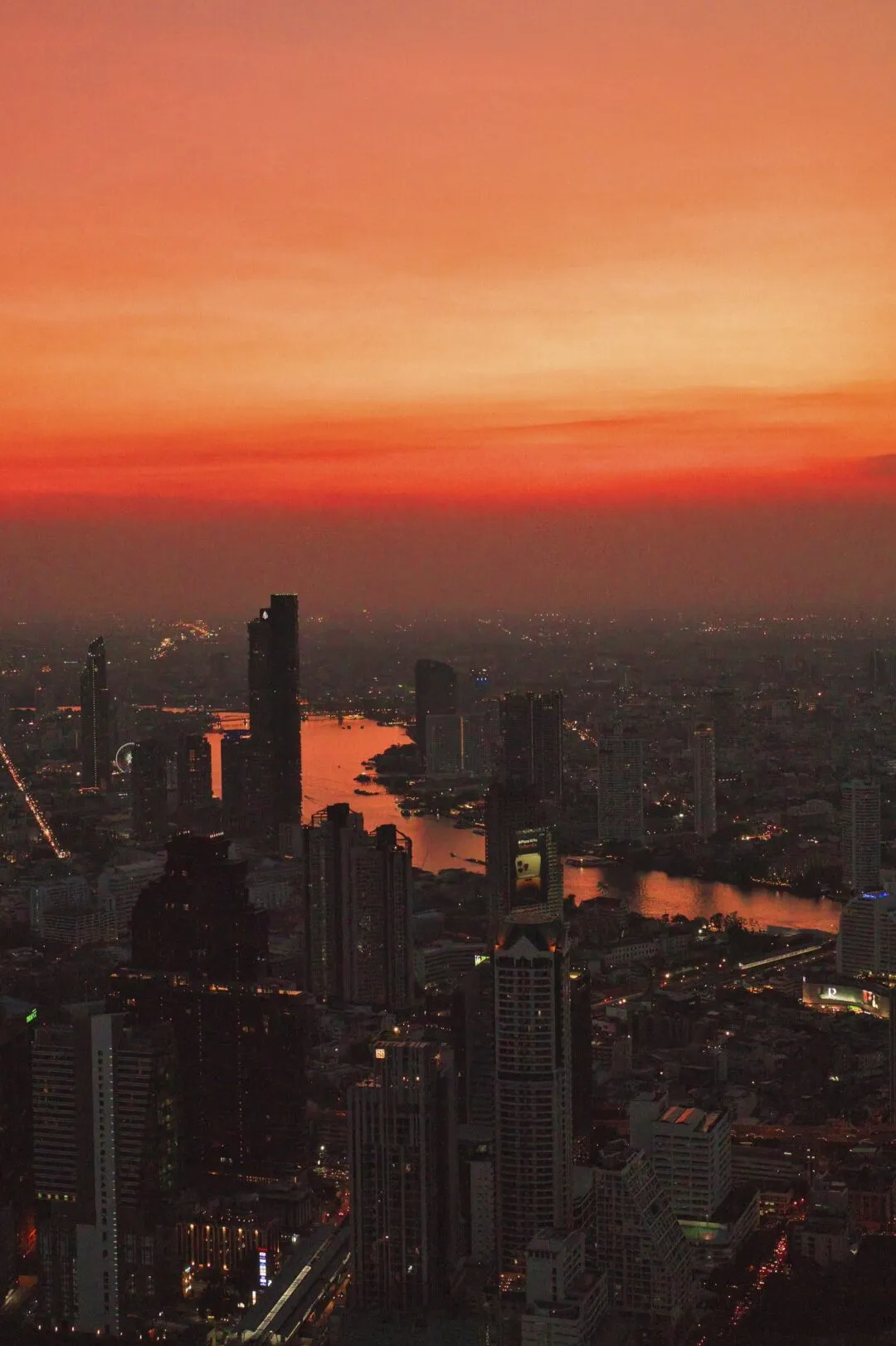 A river bend cutting through the silhouetted Bangkok skyline at dusk.