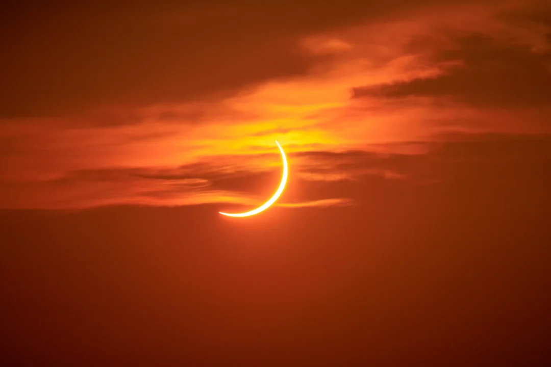 The crescent sun partly softened behind a veil of thin cloud during the Ibiza solar eclipse sunset
