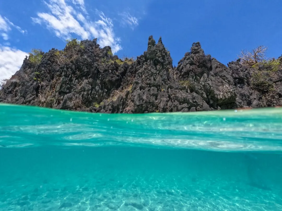 Split shot jagged karst pinnacles blue sky El Nido