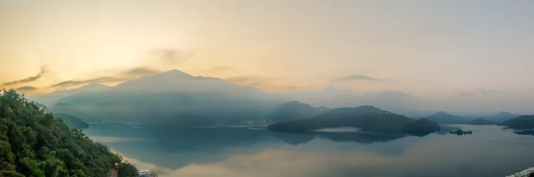 Wide sunrise panorama over Sun Moon Lake with mountain reflections, Taiwan