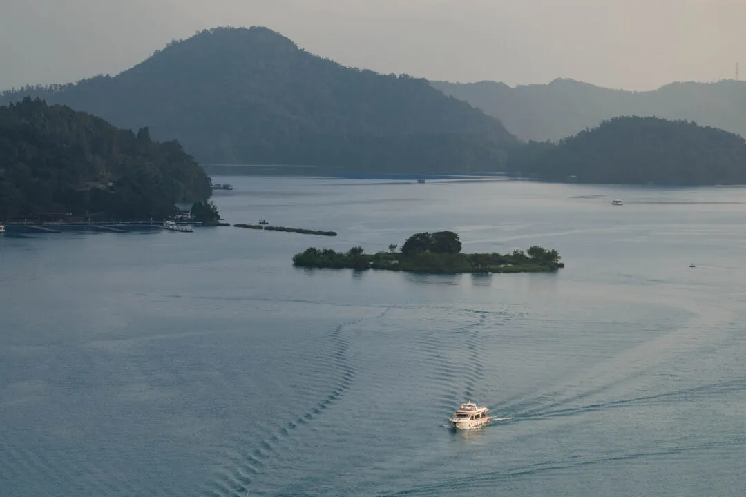 Lake view with a small tour boat cutting a wake past forested islands, Sun Moon Lake, Taiwan