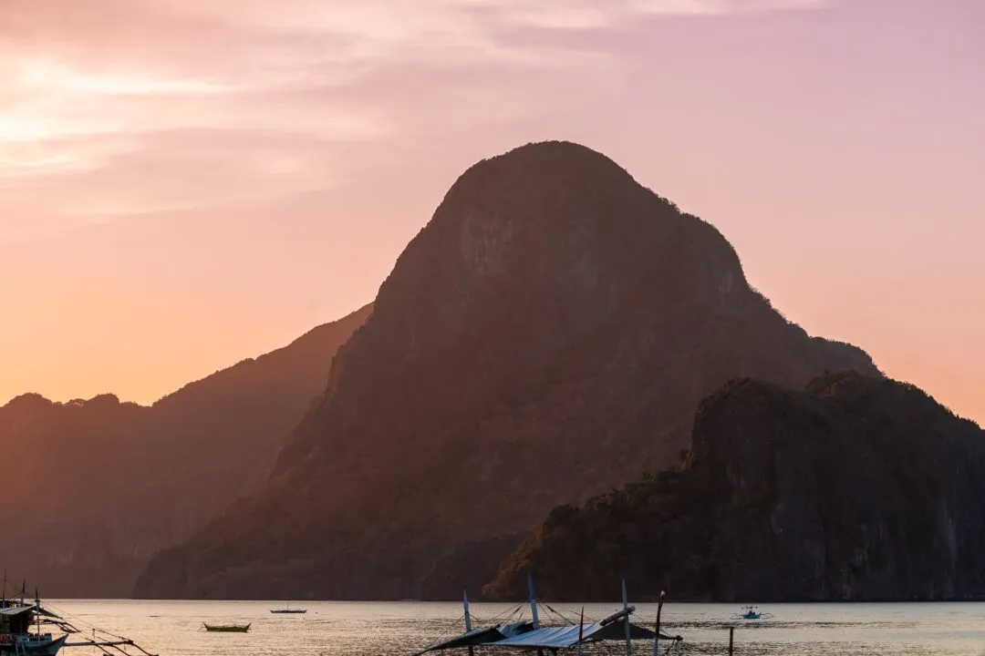 Sunset karst silhouette boats pink orange sky El Nido
