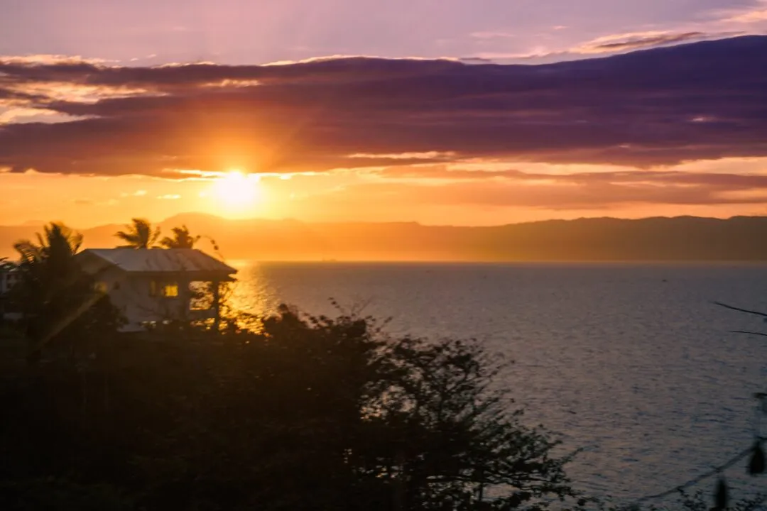Sunset silhouette house trees water cebu