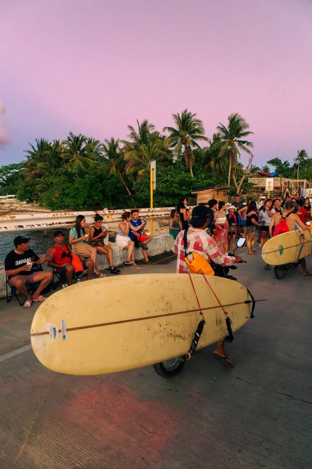 Surfer beachfront crowd pastel sky siargao
