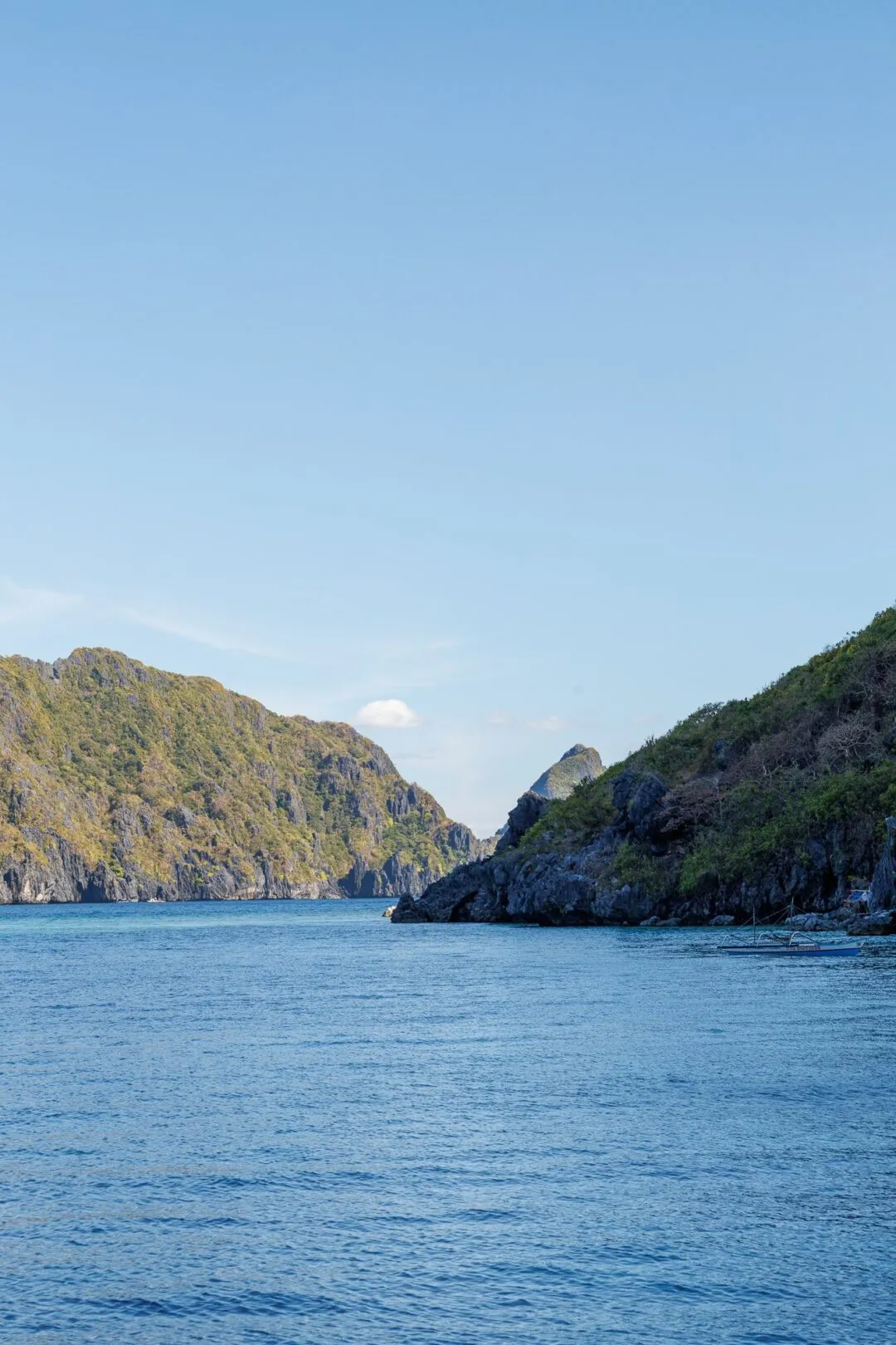 Symmetrical karst channel distant boat El Nido