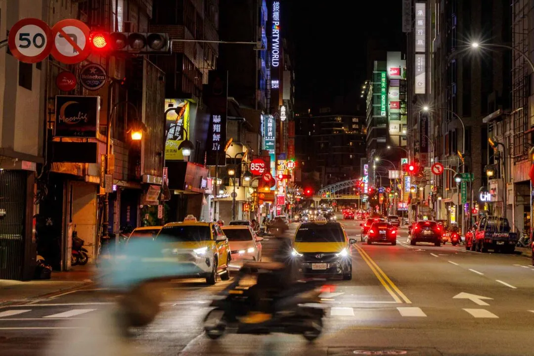 Moody neon traffic street at night with a motion-blurred motorcycle, Taichung, Taiwan