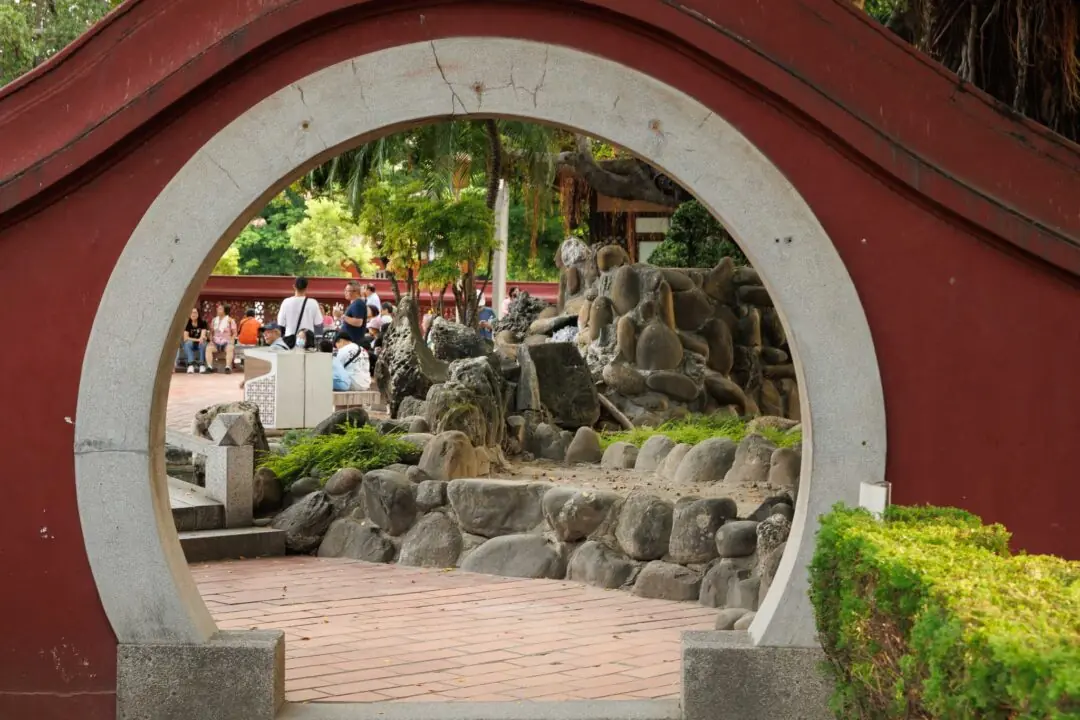 Empty circular moon gate framing a rock garden against a red wall, Tainan, Taiwan