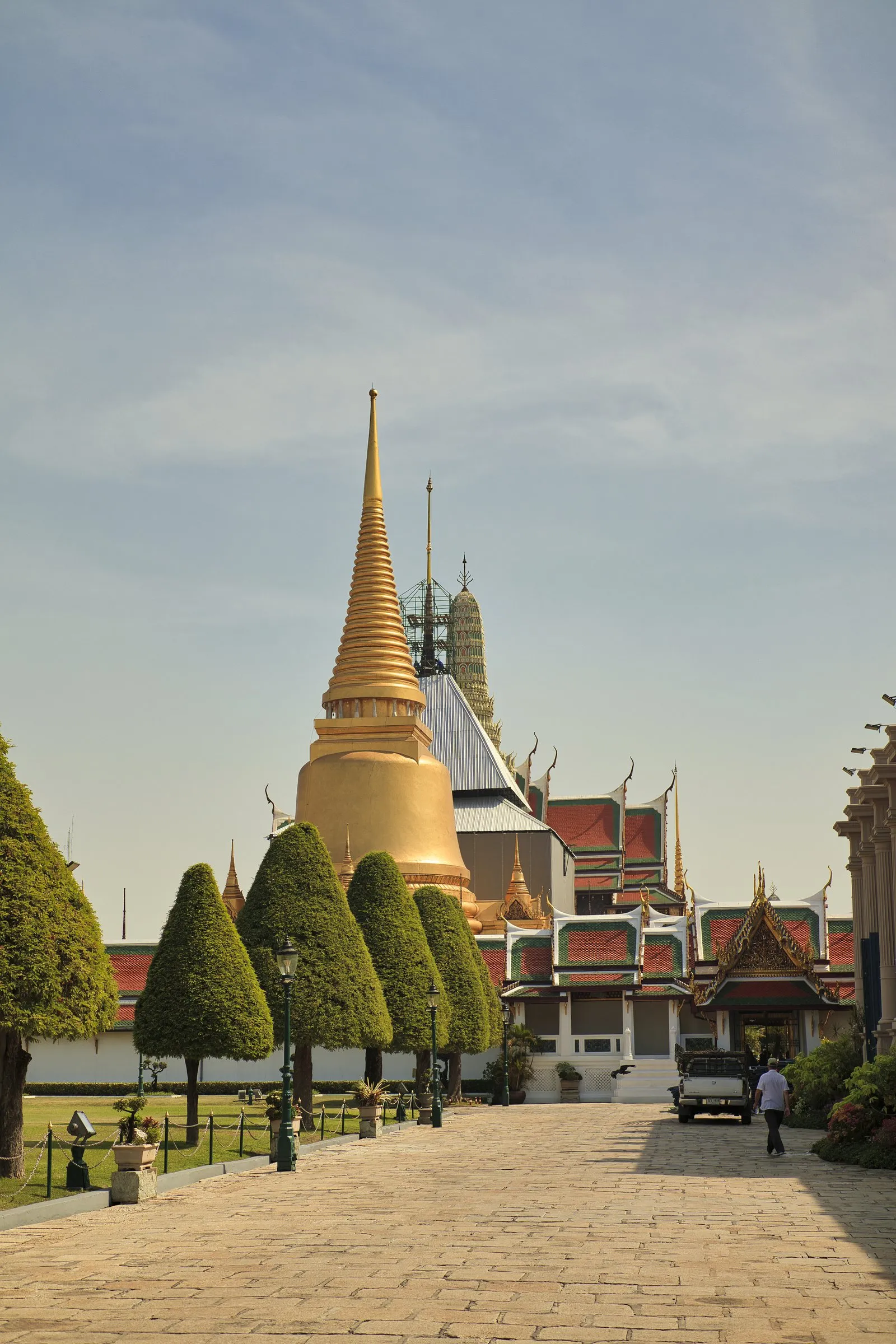 A stone pathway leading towards a gilded chedi in a grand temple courtyard in Bangkok, Thailand.