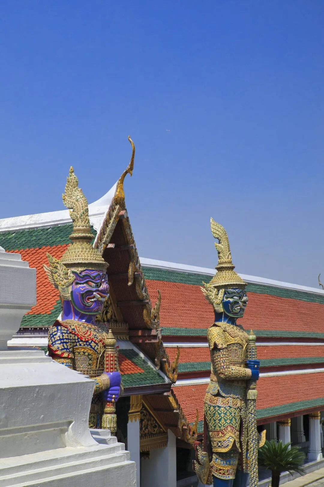 A pair of vividly painted guardian statues at a shrine entrance in Bangkok, Thailand.