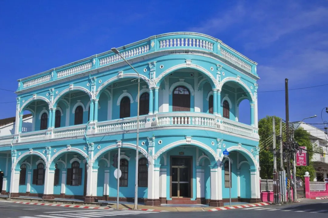 A vivid turquoise Sino-Portuguese heritage shophouse on a street corner in Phuket Old Town.