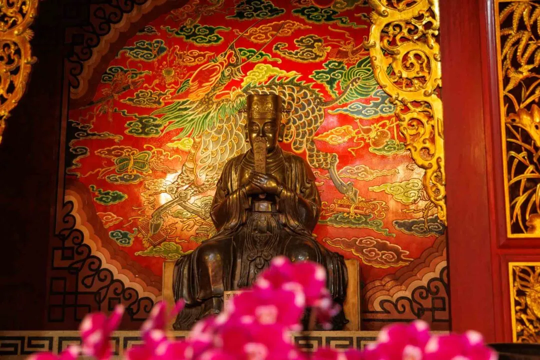 Bronze statue at Wenwu Temple lit against a red and gold phoenix mural, Sun Moon Lake, Taiwan