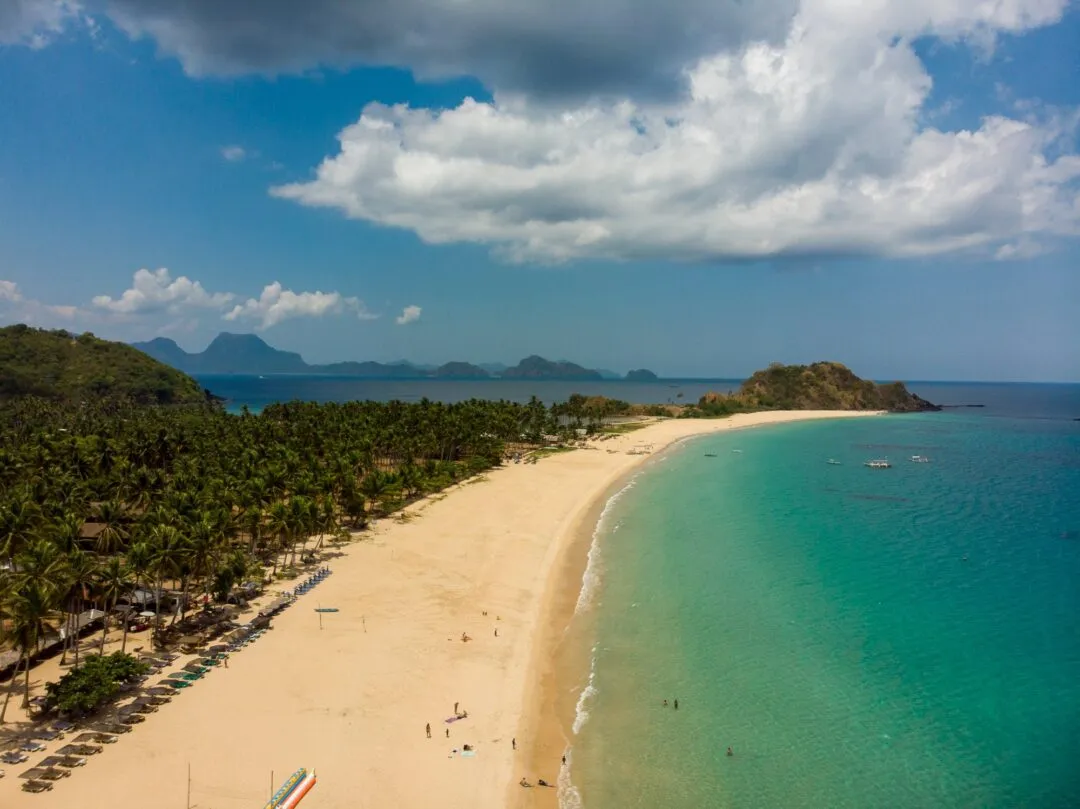 Wide aerial palm beach dramatic clouds El Nido
