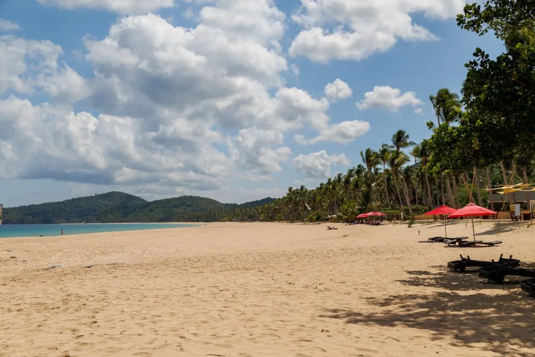 Wide beach palms umbrellas resort context El Nido