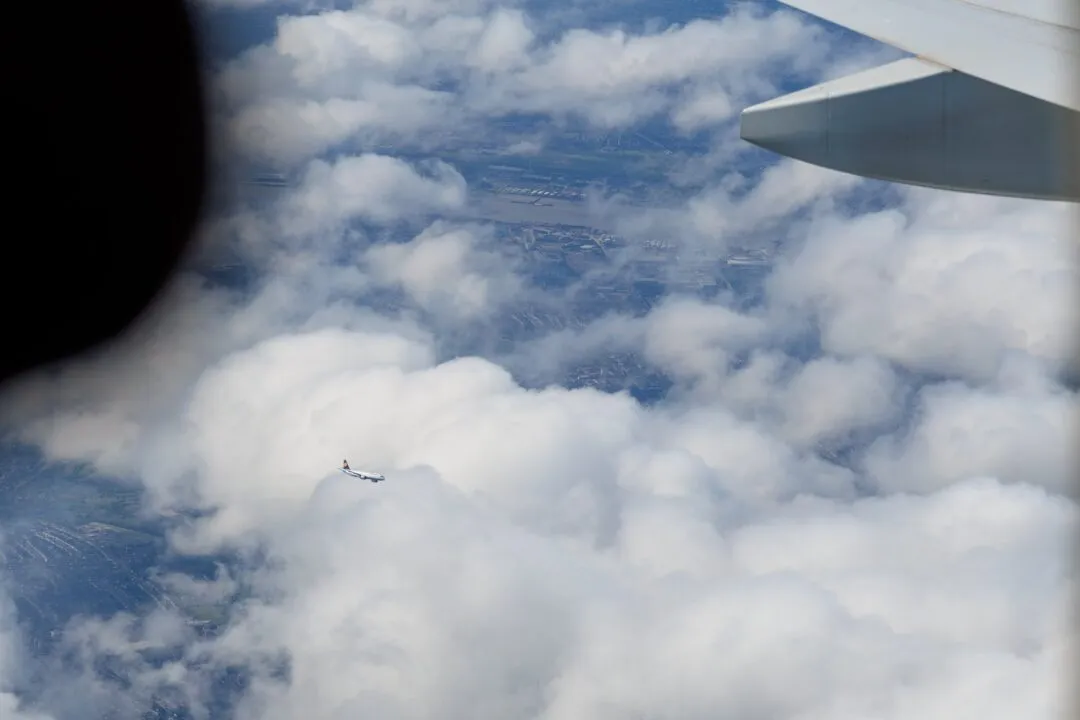 Wingtip layered clouds distant plane manila
